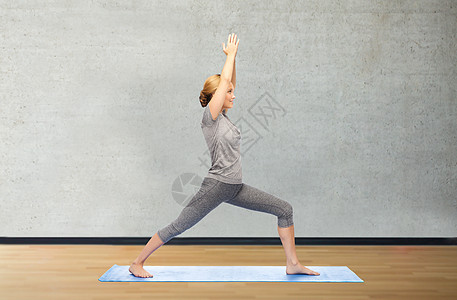 健身,运动,人健康的生活方式妇女瑜伽战士姿势垫子上的健身房背景图片