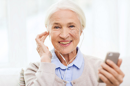技术,龄人的快乐的老妇女与智能手机耳机家里听音乐图片