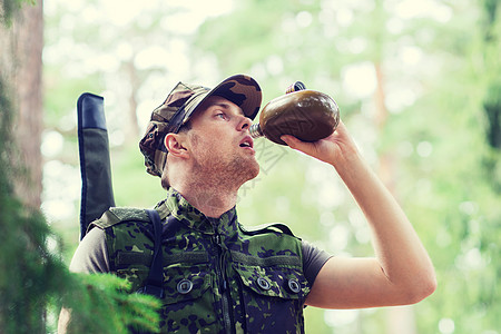 徒步旅行,轻的士兵护林员用森林里的烧瓶里喝背景图片