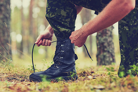 徒步旅行,近距离的士兵靴子手绑鞋带森林里图片