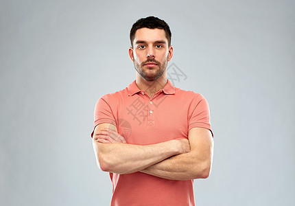 人们的严肃的轻人穿着马球T恤,交叉手臂灰色背景上灰色背景上交叉双臂的轻人图片
