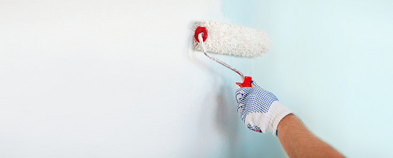 修理,建筑家庭男手套油漆墙与滚筒图片