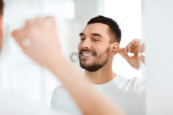 美丽,卫生人的微笑的轻人用棉签清洁耳朵,家里的浴室看镜子图片