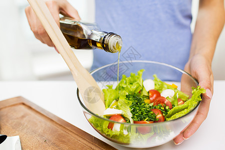 健康饮食,素食,饮食人们的密切轻妇女家里用橄榄油调味蔬菜沙拉图片