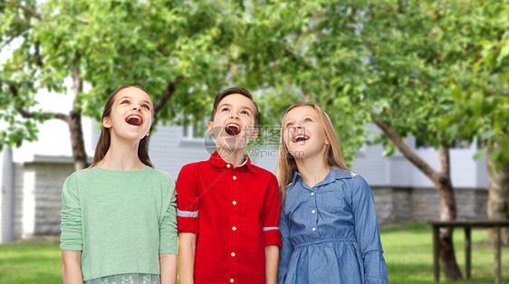童,时尚,友谊人的快乐惊讶的男孩女孩张开嘴巴仰望私人住宅后院的背景图片