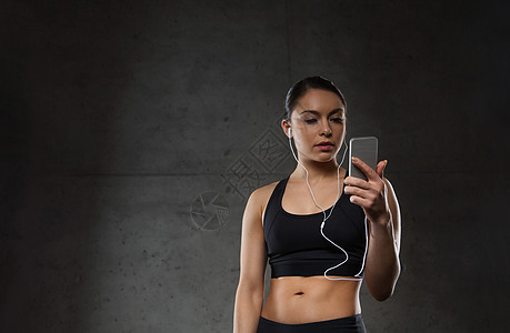 运动,健身,技术人的轻的女人智能手机耳机健身房听音乐图片