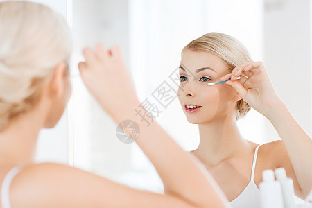 美丽,卫生人的微笑的轻女人用棉签化妆,家里的浴室看镜子图片