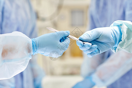 外科,医学人的外科医生的手与手术刀手术室医院背景图片