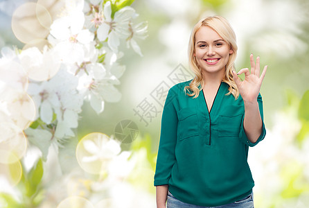 春天,手势,加上大小人的微笑的轻女人穿着衬衫牛仔裤,自然樱花背景上OK手标志图片