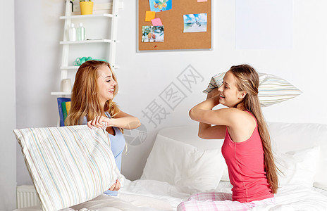 友谊,人们睡衣派的快乐的朋友十几岁的女孩家里睡觉玩枕头打架图片
