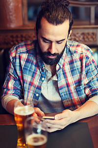 人技术男人与智能手机喝啤酒阅读信息酒吧智能手机的男人酒吧喝啤酒图片