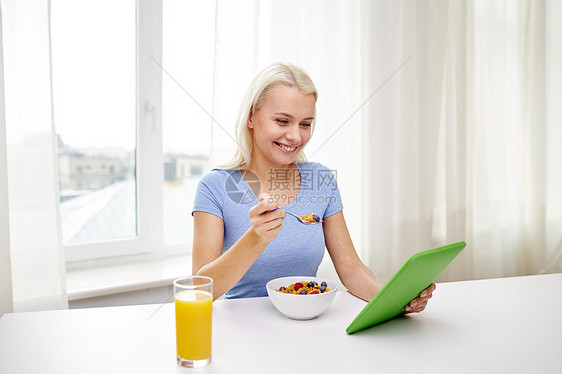 健康饮食,饮食,技术人的微笑的轻妇女与平板电脑电脑家里吃早餐图片