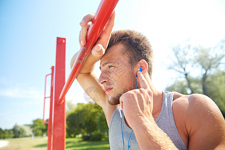 健身,运动,训练生活方式的轻人带着耳机听音乐,户外的水平酒吧锻炼图片