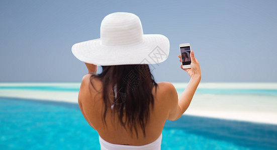 生活方式,休闲,夏天,技术人的微笑的轻妇女十几岁的女孩戴着太阳帽自拍与智能手机海滩游泳池背景图片