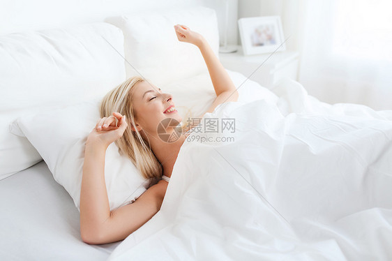 休息,睡觉,舒适人的轻的女人床上伸展家里的卧室图片