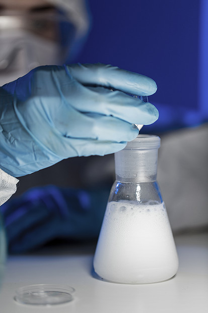 科学化学生物学医学人的轻的女科学家把化学粉末倒进烧瓶试验临床实验