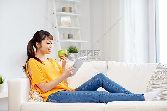 人,健康的饮食,教育,技术快乐的轻亚洲妇女坐沙发上与平板电脑绿色苹果家里图片