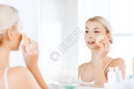 美容,皮肤护理人的微笑的轻洗她的脸与部清洁海绵浴室图片