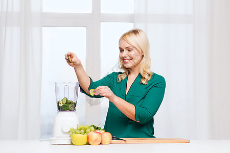 健康的饮食,烹饪,素食,饮食人的微笑的轻妇女把水果蔬菜放入搅拌机家里厨房图片