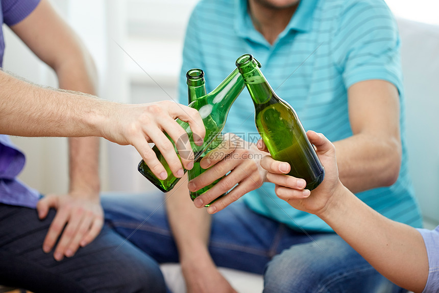 友谊酒精人庆祝节日的亲密的男朋友家里喝酒碰啤酒瓶