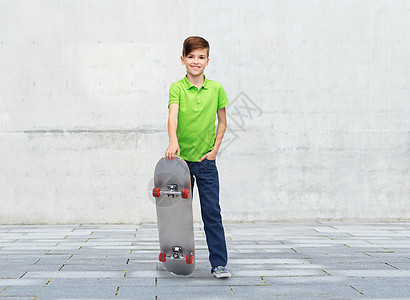 童,休闲,学校人的快乐的微笑男孩与滑板混凝土灰色墙壁上的城市街道背景图片