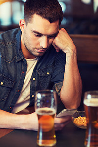 人技术男人与智能手机喝啤酒阅读信息酒吧智能手机的男人酒吧喝啤酒图片