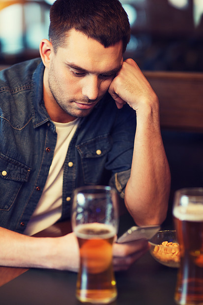 人技术男人与智能手机喝啤酒阅读信息酒吧智能手机的男人酒吧喝啤酒图片