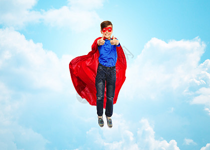 幸福,自由,童,运动人的男孩穿着红色超级英雄斗篷具空中飞翔,蓝天云层背景上竖大拇指图片