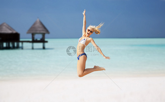 人,旅游,暑假假期的快乐的轻女人跳过异国情调的马尔代夫海滩与平房背景图片