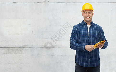 维修建筑施工人员维修理念戴着手套戴着头盔的微笑人,戴着灰色混凝土墙背景图片
