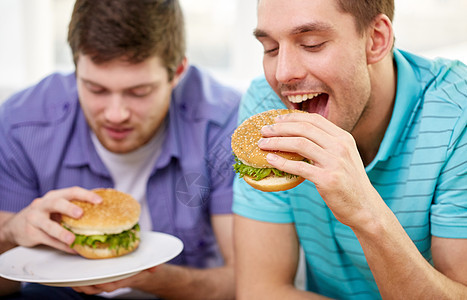 快餐,健康的饮食,人垃圾食品亲密的快乐朋友家里吃汉堡包图片