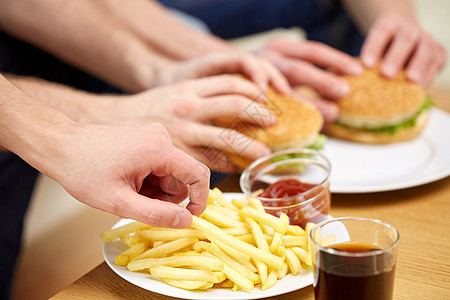 快餐,健康的饮食,人垃圾食品家里的桌子上放着炸薯条汉堡包图片