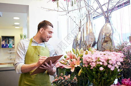 人,销售,零售,商业花卉快乐微笑的花店男子与剪贴板写作笔记订单花店图片