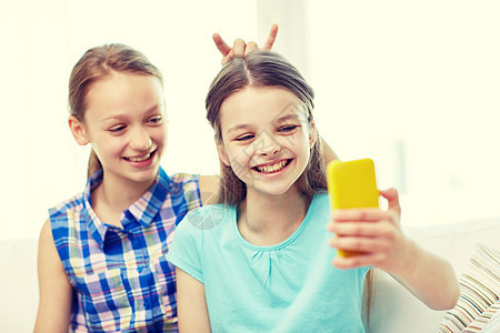 人,孩子,技术,朋友友谊的快乐的小女孩自拍智能手机自拍,家玩得开心图片