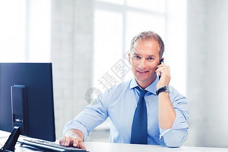商业技术微笑的商人与智能手机办公室微笑的商人,办公室里智能手机图片