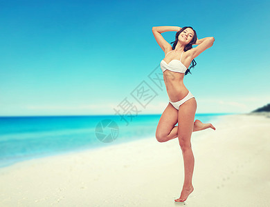 人,泳装,旅游,旅游夏季快乐的轻女人穿着白色比基尼泳衣,举手,站条腿上的海滩背景图片