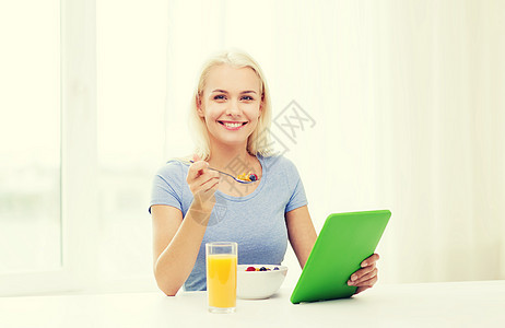 健康的饮食,饮食人的微笑的轻妇女与平板电脑家里吃早餐图片