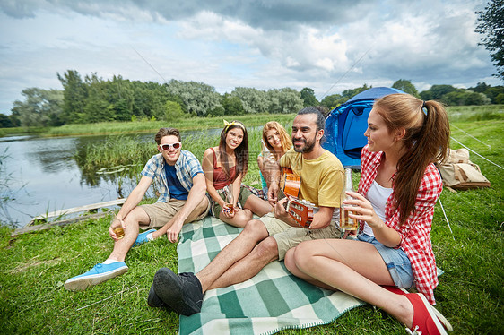 旅行,旅游,徒步旅行,野餐人们的群快乐的朋友带着帐篷饮料,露营时弹吉他图片