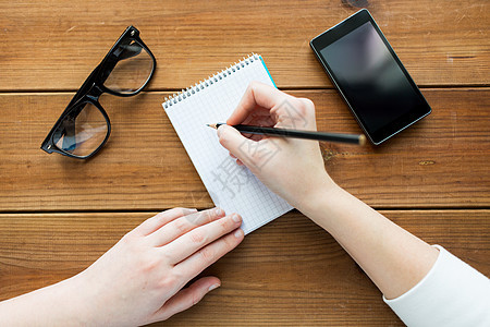 教育商业人的密切妇女学生写信给记事本,铅笔眼镜,智能手机木桌上图片