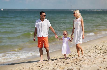 家庭,假期,收养人的快乐的男人,女人小女孩戴着太阳镜夏天的海滩上散步图片