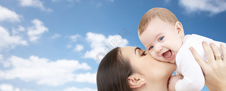 家庭,母亲,父母,爱幸福的人的快乐的母亲亲吻她的孩子蓝天云彩的背景图片