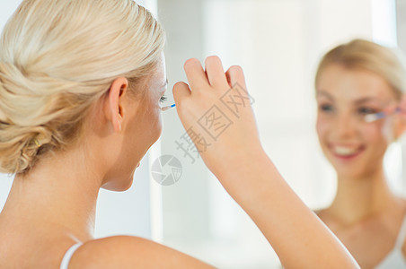 美丽,卫生人的近距离微笑的轻妇女用棉签化妆家里的浴室看镜子图片