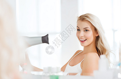 美丽,发型,早晨人的微笑的轻女人用扇子干她的头发,看着镜子家里的浴室图片