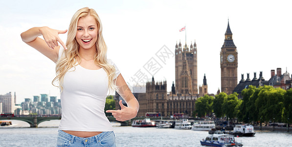 情感,旅游,广告人的快乐的微笑轻妇女十几岁的女孩穿白色T恤指着自己伦敦城市大本塔背景图片