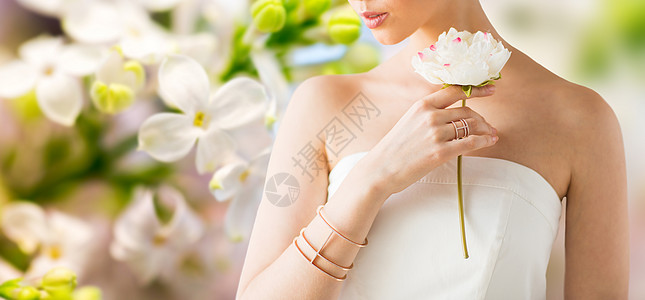 魅力,美丽,珠宝奢侈的美丽的女人与黄金戒指手镯举行花自然春天丁香花背景图片