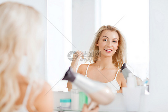 美丽,发型,早晨人的微笑的轻女人用扇子干她的头发,看着镜子家里的浴室图片
