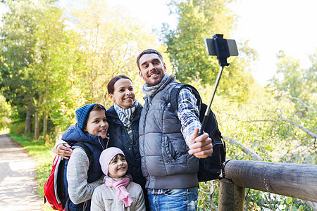 技术,旅游,徒步旅行人们的快乐的家庭与背包拍照智能手机自拍棒徒步旅行图片