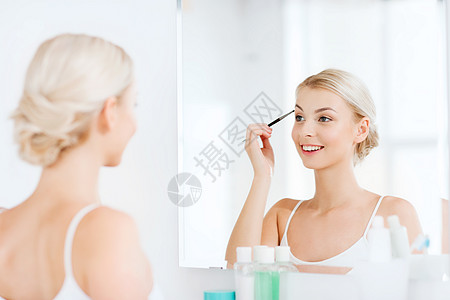 美容,化妆,化妆品,早晨人的轻的女人用刷子画眉,家里的浴室照镜子背景图片