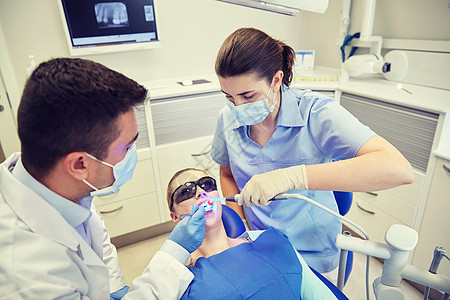 人,医学,口腔医学保健男牙医助理与牙科治疗光镜子治疗女病人牙齿牙科诊所办公室图片