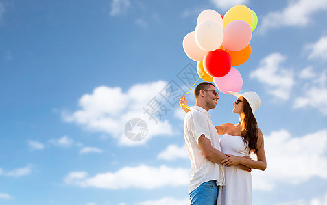 爱情,假期,夏天,约会人的微笑的夫妇戴着太阳镜,气球拥抱蓝天背景上图片